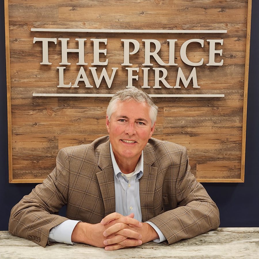 Attorney Bill Price seated beneath The Price Law Firm sign at the Panama City office