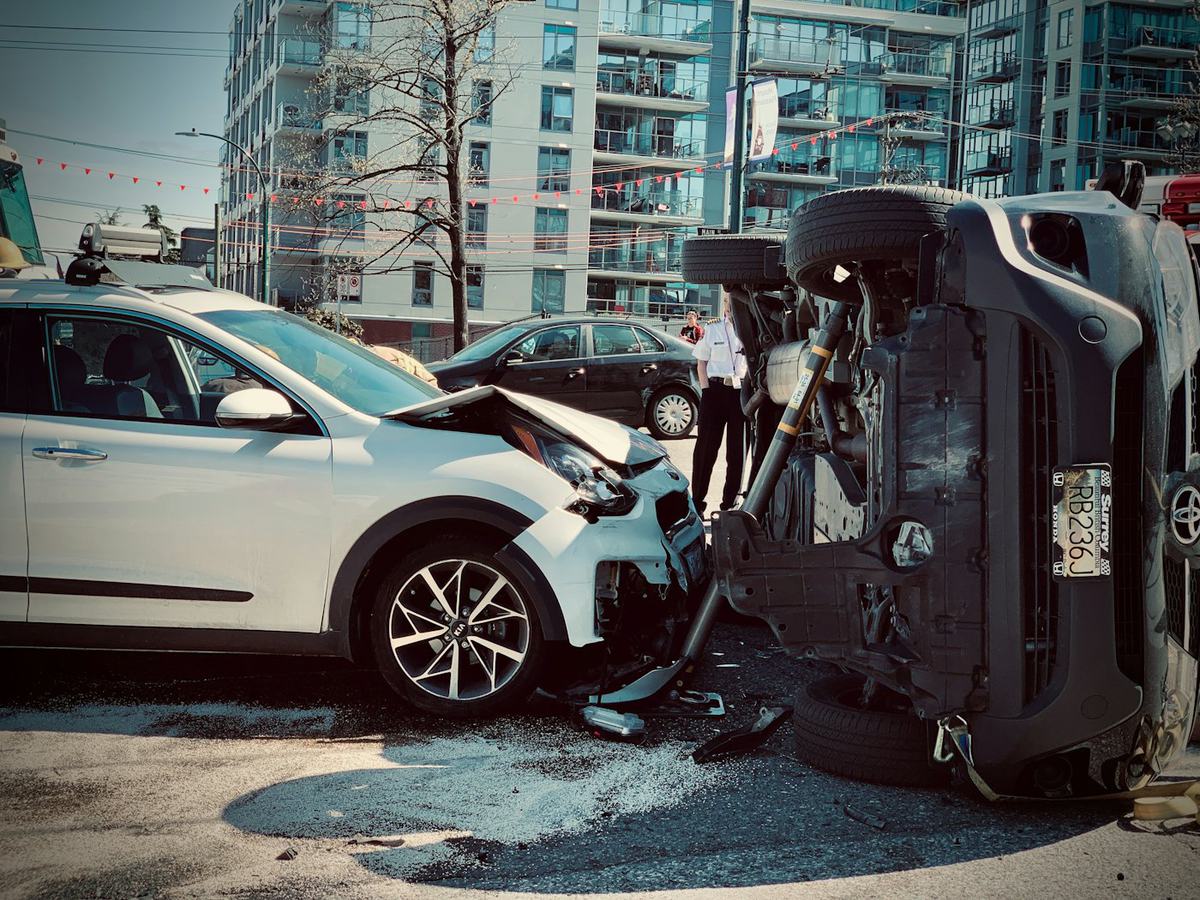 A car with front-end damage beside an overturned vehicle after a collision