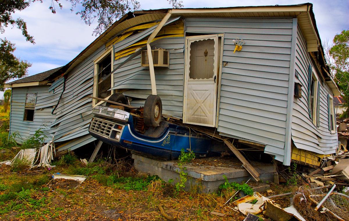 A house severely damaged by a hurricane, with debris in the yard