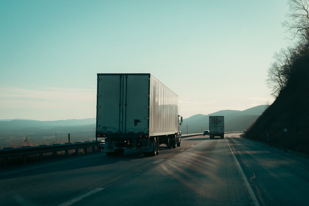 A tractor-trailer traveling on a highway at dusk